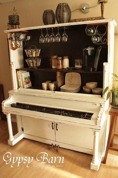 an old piano is sitting on the floor in front of a table with pots and pans