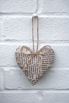 a heart shaped ornament hanging from a string on a white brick wall,