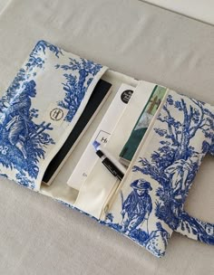 a blue and white toiler print case on a bed with the contents in it