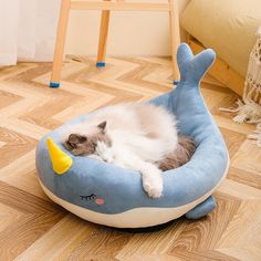 a cat sleeping in a blue whale shaped bed