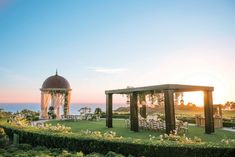 an outdoor wedding venue with gazebo and flowers in the foreground, overlooking the ocean