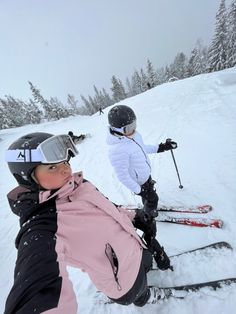 two people riding skis down a snow covered slope