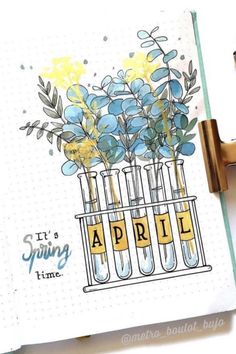 an open notebook with flowers in test tubes on the cover, and some keys next to it