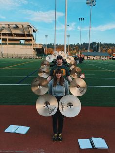 a man and woman standing on a football field holding up musical instruments in front of them