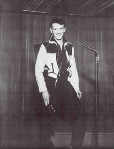 a man standing in front of a microphone and wearing a vest with numbers on it