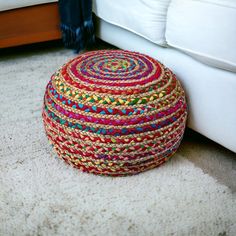 a multicolored basket sitting on the floor in front of a white couch and ottoman