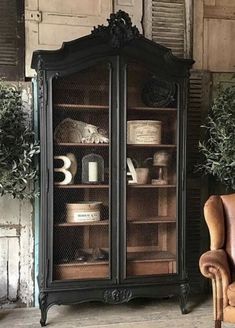 an antique china cabinet with glass doors and shelves in the middle, next to a chair