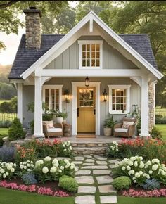 a small house with flowers and plants around the front door is featured in this image