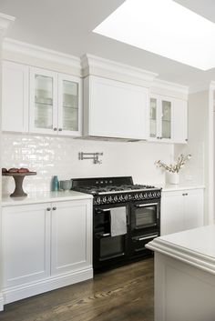 a kitchen with white cabinets and an oven in the center is shown, as well as a skylight above it