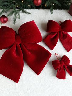 three red bows on top of a white towel next to a christmas tree with ornaments