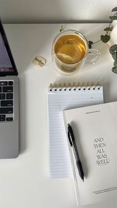 an open laptop computer sitting on top of a desk next to a cup of tea