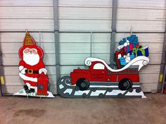 two cardboard santas are standing in front of a garage door