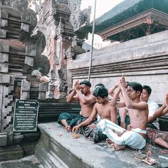 five people sitting on the ground with their hands in the air