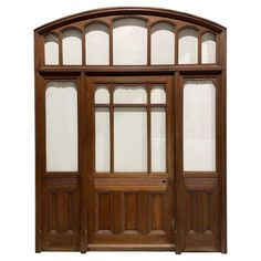 an arched wooden door with glass panels and wood trimmings on the top half