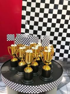 several trophies are sitting on top of a black and white checkerboard tablecloth