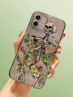 a woman's hand holding an iphone case with a skeleton and flowers on it