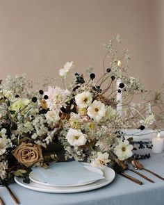 the table is set with white and black flowers, candles and napkins on it