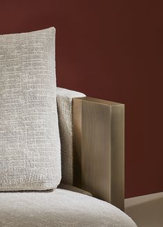 a close up of a pillow on a couch with a red wall in the background