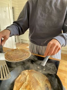 a person cooking pancakes in a skillet on top of a stove with a spatula