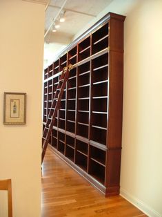 an empty room with bookshelves in the middle and a ladder leaning against the wall