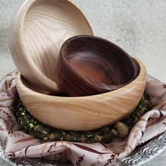 two wooden spoons are sitting in a bowl on a plate with a pink and white cloth