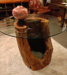 a glass table with a wooden base on carpeted flooring in front of a couch