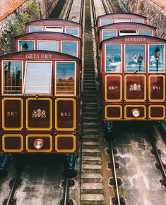 two trolley cars sitting side by side on the tracks