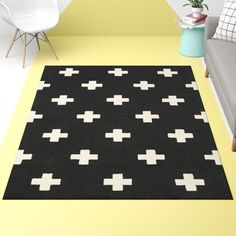 a black and white rug with crosses is on the floor in front of a couch