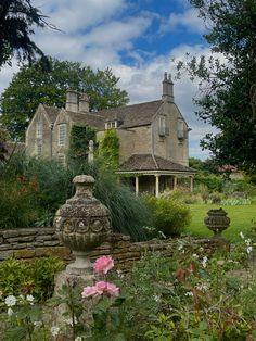 an old stone house surrounded by flowers and greenery