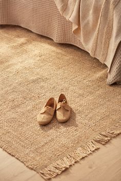 a pair of shoes sitting on top of a bed next to a pillow and blanket