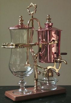 a silver coffee pot and two goblets sitting on a table next to each other