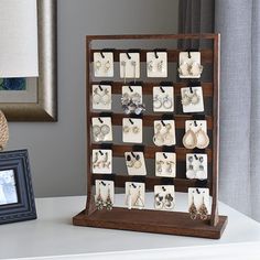 a display case with earrings and jewelry on it next to a framed photo in front of a window