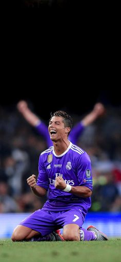 a soccer player sitting on the ground with his arms in the air