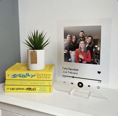 a couple of books sitting on top of a white shelf next to a potted plant