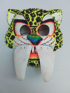 an animal mask with large eyes and long ears, painted in bright colors on a gray background