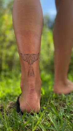 a person with a tattoo on their foot walking in the grass and looking at the ground