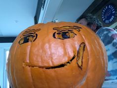 a man standing next to a large pumpkin with faces drawn on it's face