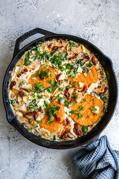 a skillet filled with pasta and sauce on top of a counter next to a pair of gloves