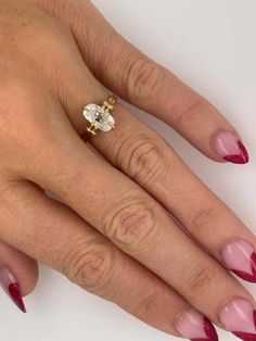 a woman's hand with red and pink manicured nails holding a diamond ring