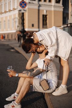 two people are sitting on the curb and one is holding a wine glass in his hand