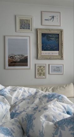 a bed with blue and white comforter next to pictures on the wall