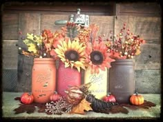 an arrangement of mason jars with sunflowers and autumn leaves