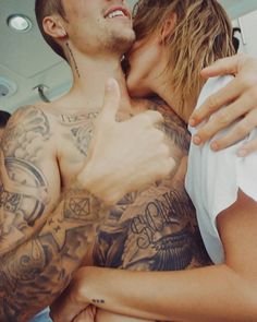 a man and woman embracing each other in the bed with tattoos on their chests