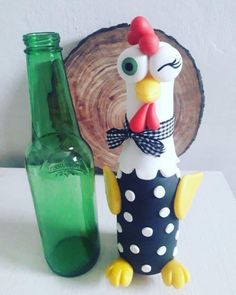 a chicken figurine sitting next to a green bottle