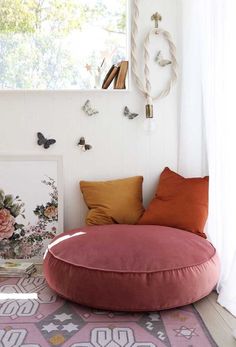 a pink bean bag chair sitting on top of a rug in front of a window