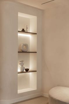 a white room with shelves and vases on the wall