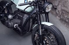 a white and black motorcycle parked in front of a stone wall with an emblem on it