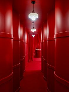 an empty hallway with red walls and drapes on the ceiling, along with round lights