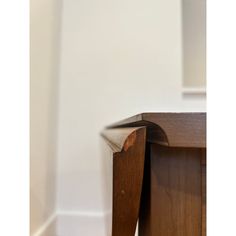 the corner of a wooden table with white walls