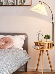 a bed room with a neatly made bed and a lamp on the side table next to it